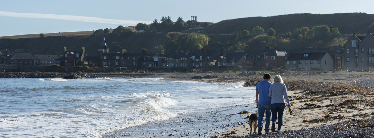 Couple walking with their dog on Stonehaven beach