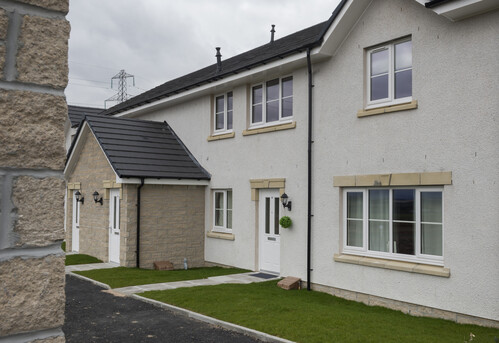 A photo of a row of new terraced housing. Three properties in total are in the shot, with small grassed areas in front of them. 
