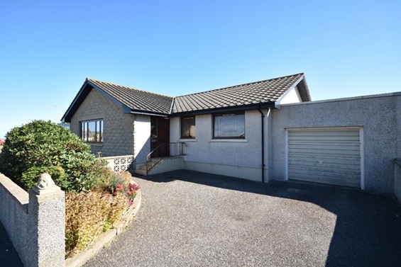 Front of semi detached bungalow with stairs up to front door, driveway and garage