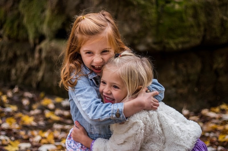 Two girls smiling and hugging each other