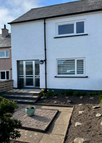 Mid-terraced house with paved path leading up to front door which has three steps