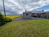 Front of 2 Fordafourie Cottage, showing a bungalow house with grass area and paved area around house