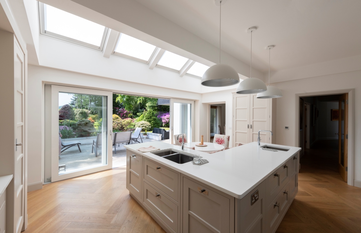 Inside the Beeches, kitchen island with 3 hanging lamps and large glass doors