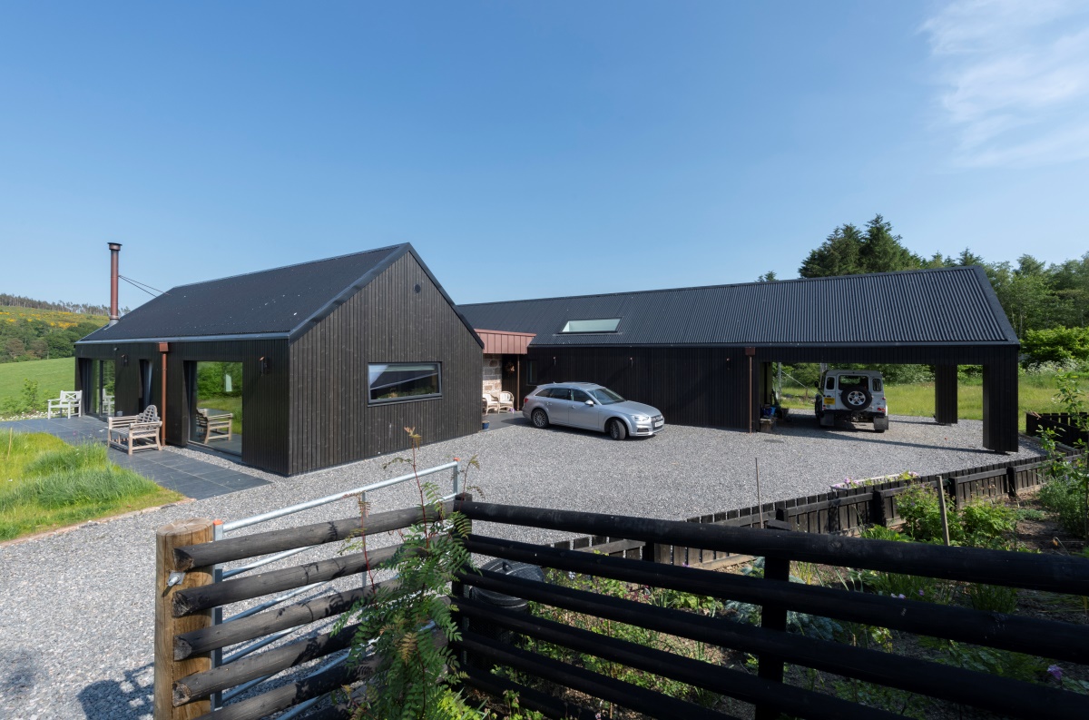 Building with gravel driveway and parking space behind building, fencing in foreground