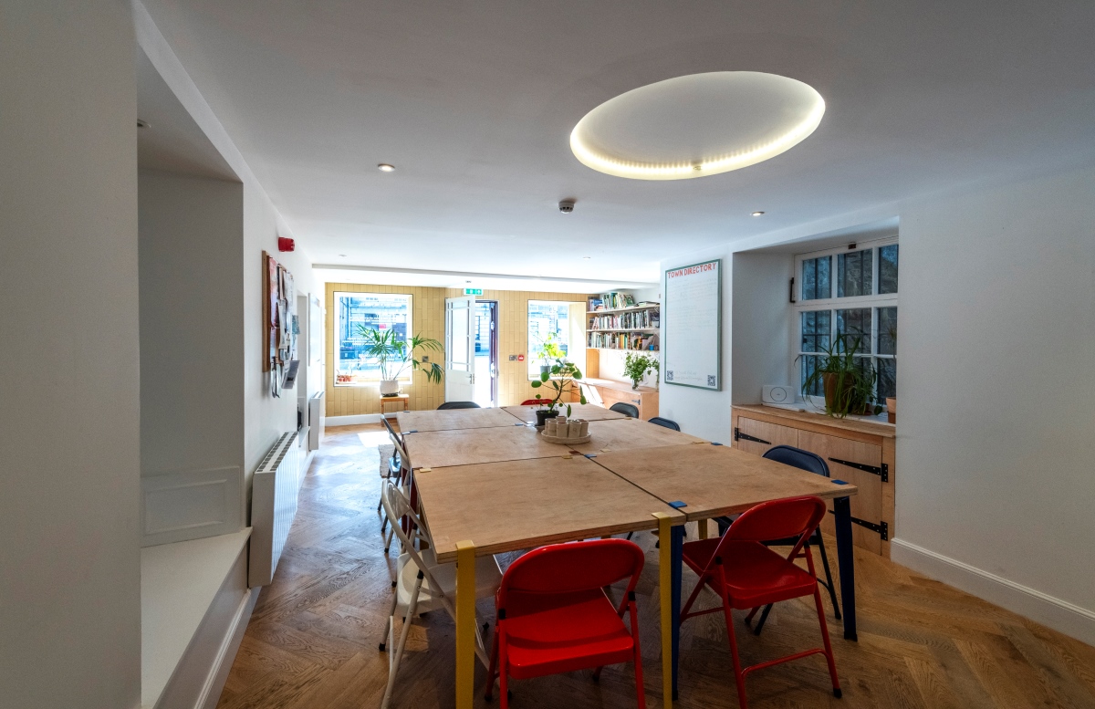 Room with wooden floors, large table in centre and large windows at the back