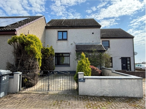 Mid-terraced house with gated driveway and tall bushes on either side of driveway