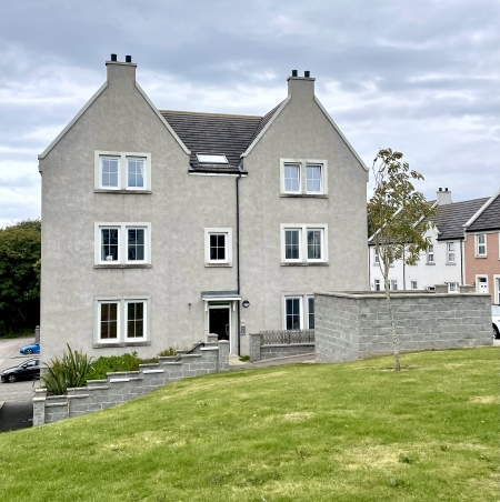 Front of block of flats, with grass area and parking area in background