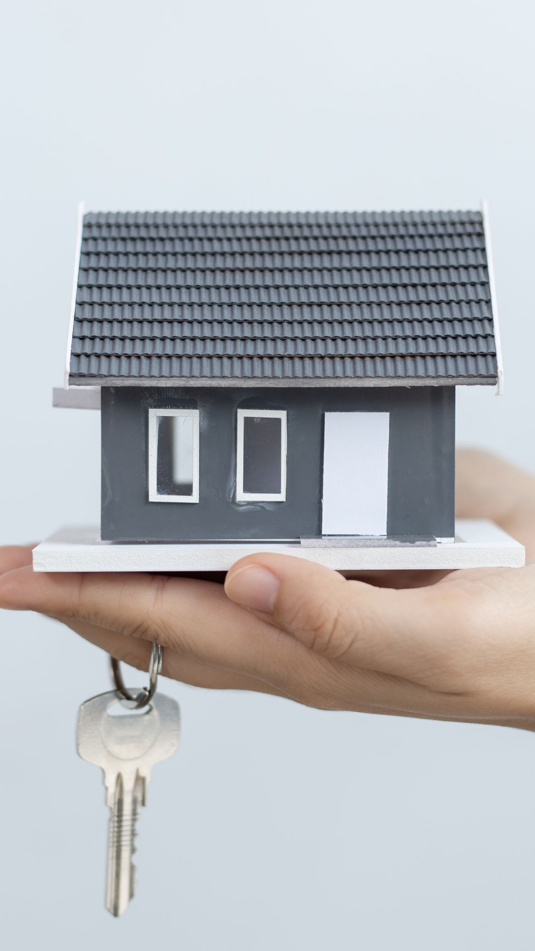 A house and a key on a hand. 
