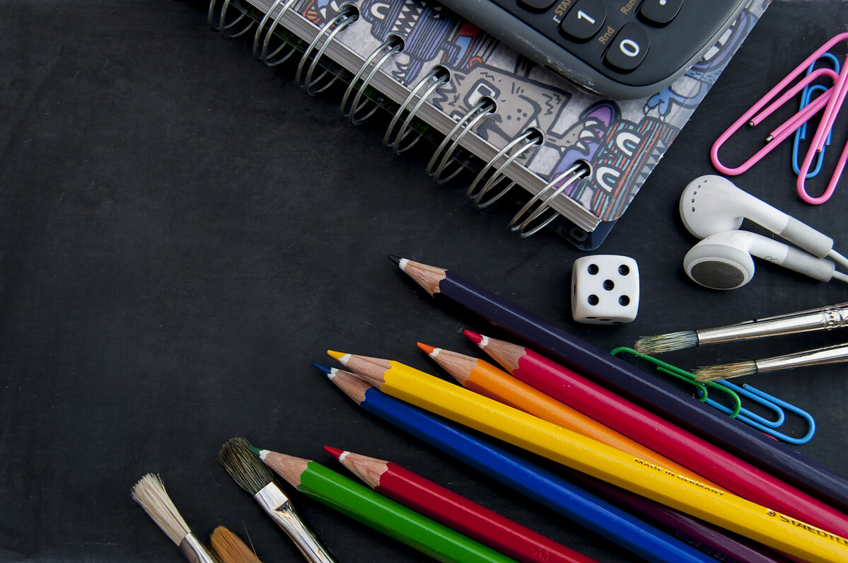 Chalkboard with with coloured pencils, note pad, calculator and earphones
