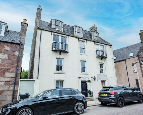 Street view of block of flats, with cars parked on the street