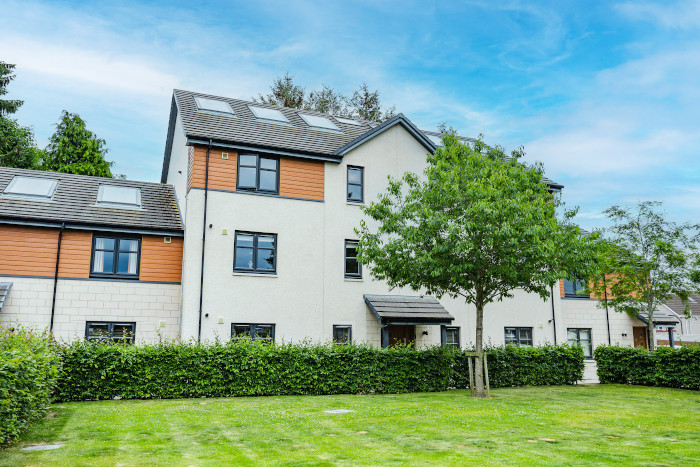 Front of the block at 12 Ambleside Court with grass, shrubs and trees