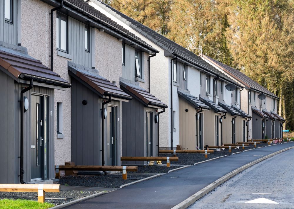A photo of a row of new houses at Nether Aden, Mintlaw. The semi-detached properties each have a porch, with a pavement and road running in front of the development. 