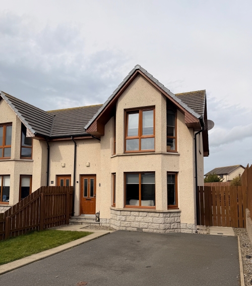 Front of property with paved driveway and small grass area 