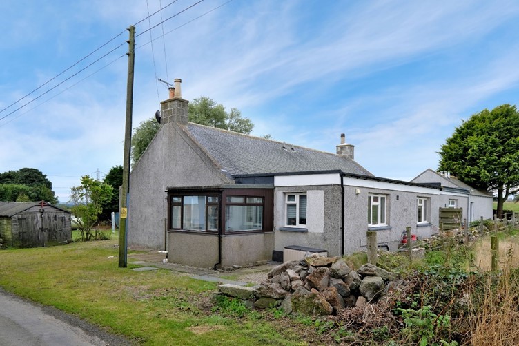 Front of the property with grass, stones and fence to the side
