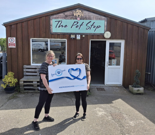 Owner in front of the Pet Stop holding a big Aberdeenshire Loves Local gift card