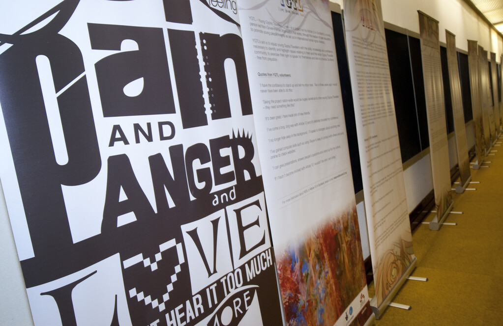 A row of display panels in a corridor with Gypsy, Traveller and Roma information on them. There is a mixture of text, photos and graphics on the panels.