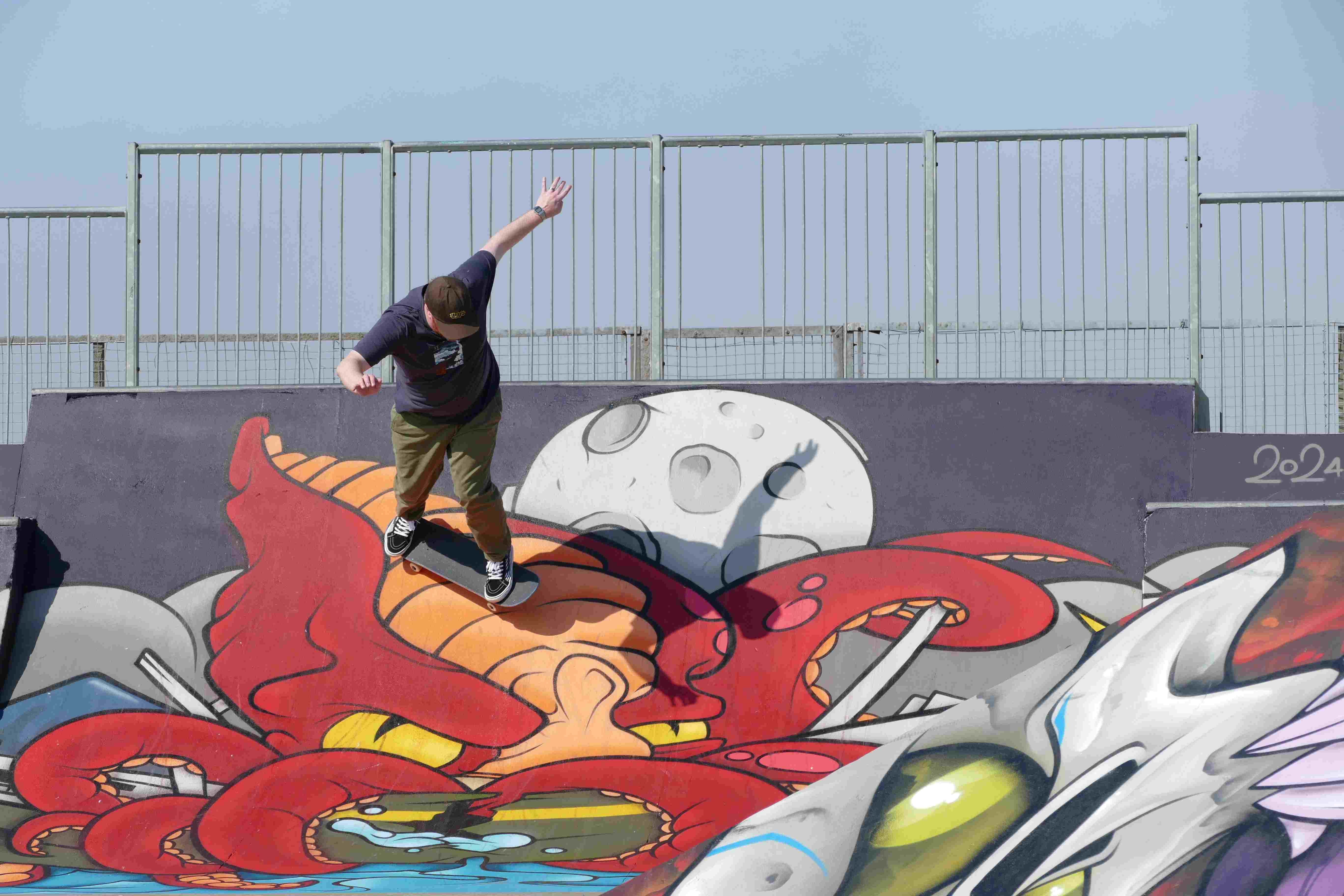 A picture of a skateboarder on a ramp decorated in colourful spraypainted graffiti