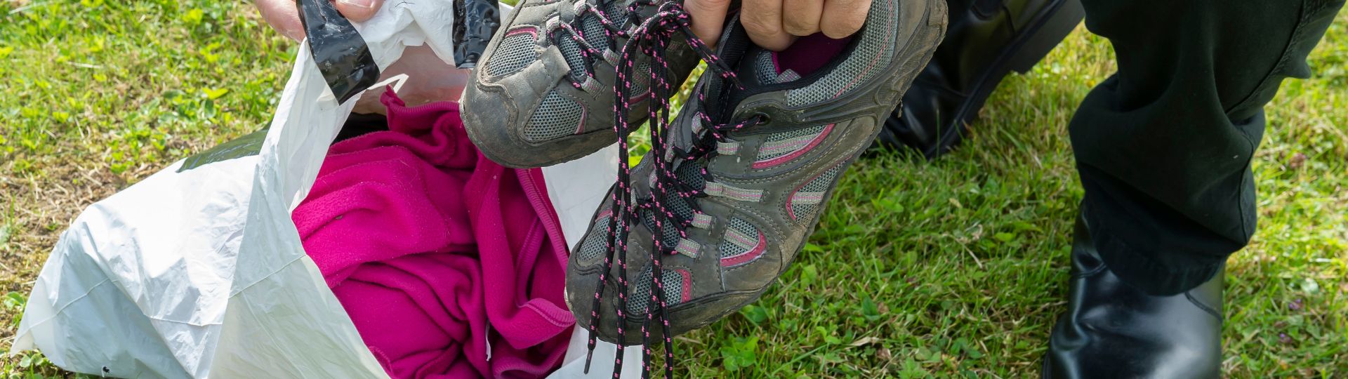 Clothes and shoes being put into a plastic bag.