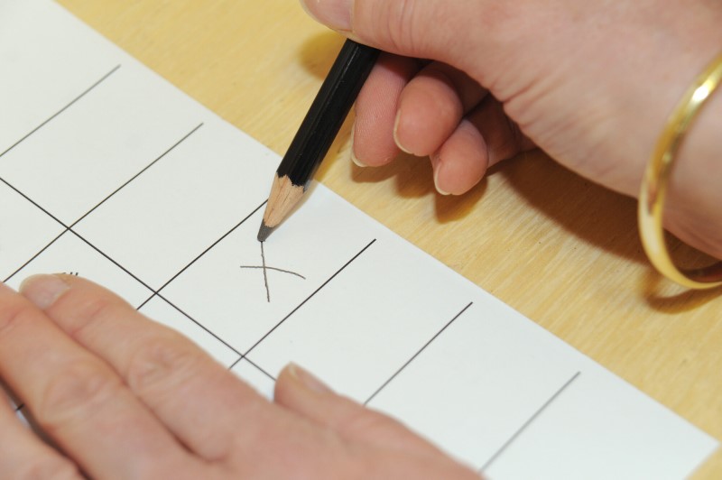 A picture of a hand making an X mark with a pencil on a form