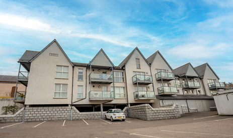 Front of property showing a block of flats with balconies and a carpark